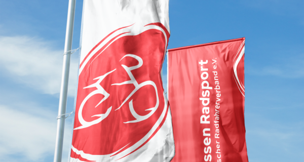 Zwei Fahnen mit dem Hessen Radsport Logo vor blauem Himmel